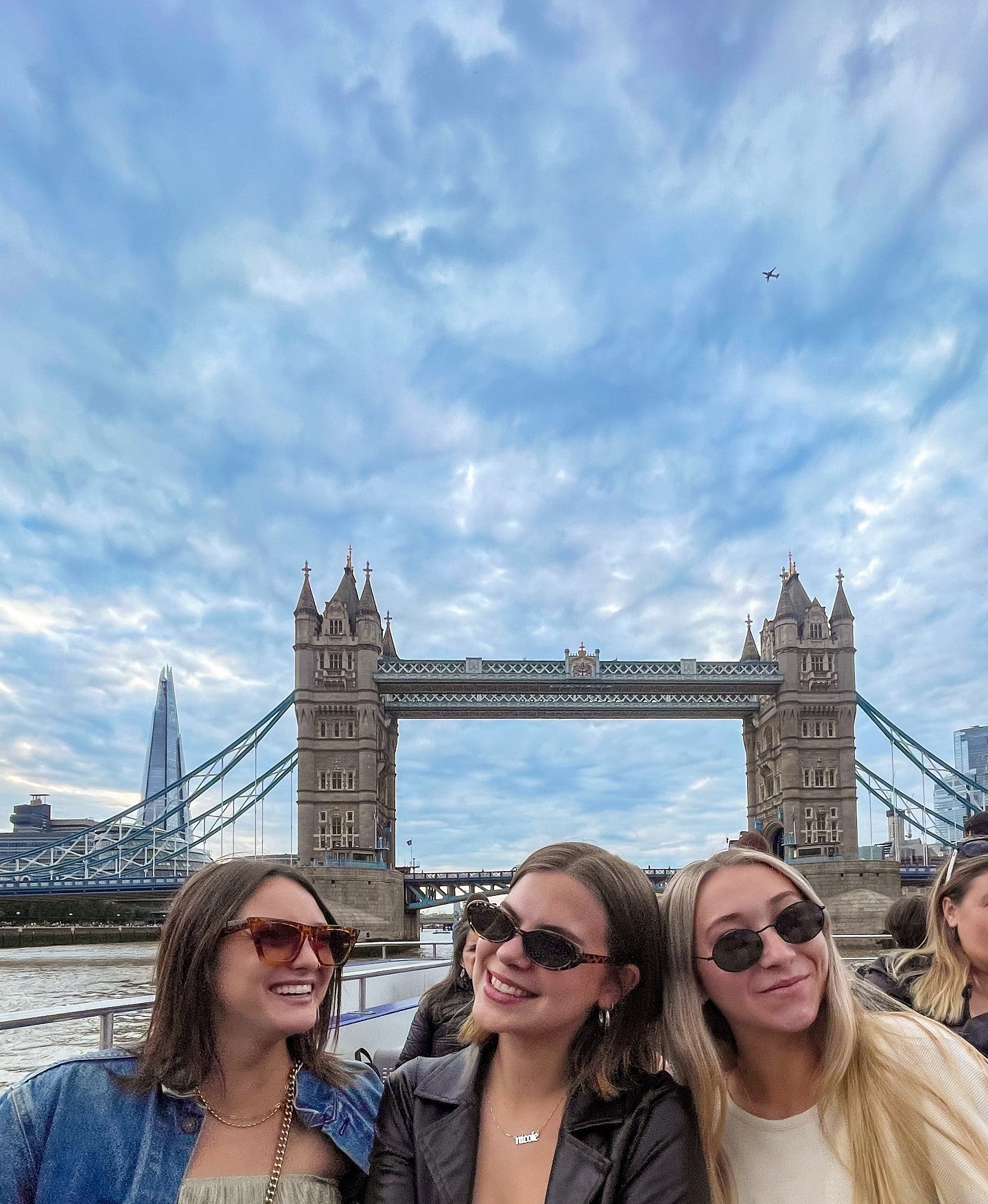three students pose in front of a bridge in London
